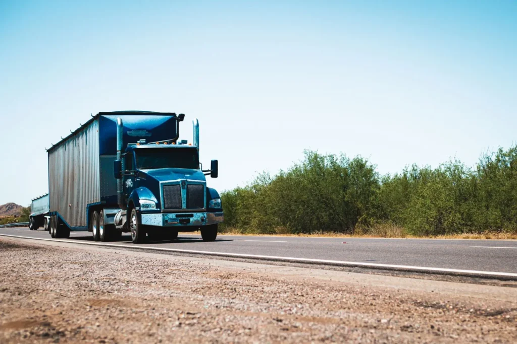 Blue semi-truck hauling an enclosed trailer on a highway