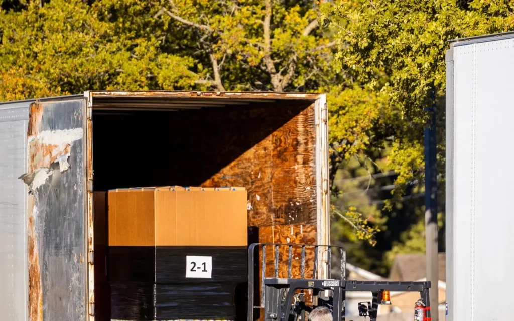 Forklift loading a pallet of boxes into a freight trailer