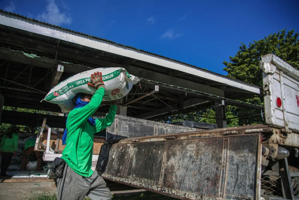 Worker loading a fertilizer bag onto a truck at a farm supply depot