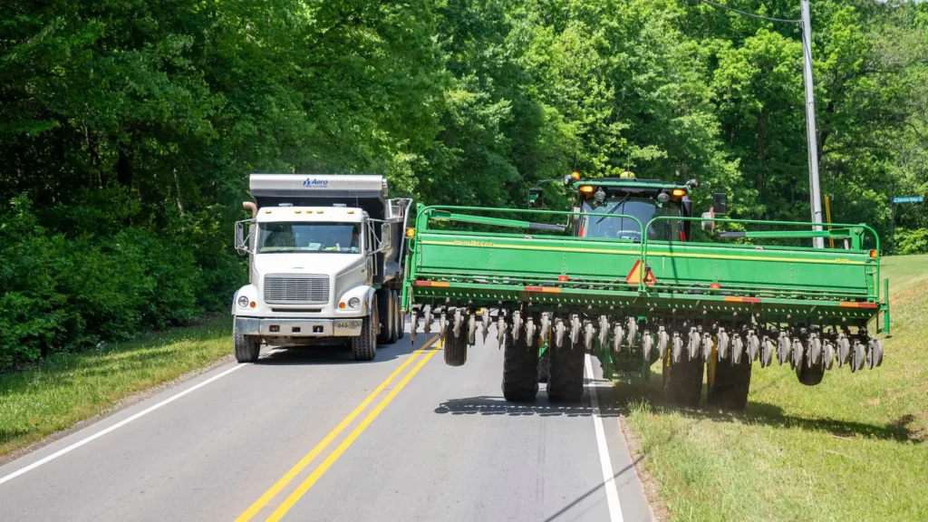 Freight truck passing large farm equipment on a rural road