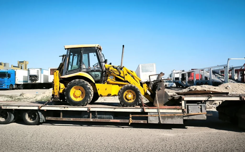 Yellow construction vehicle secured on a flatbed trailer