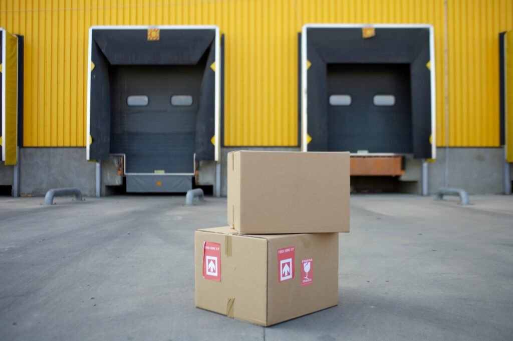 Cardboard cartons staged beside warehouse loading doors for freight pickup