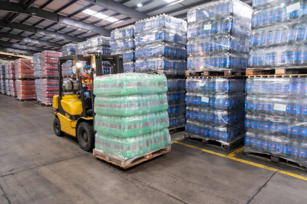 Forklift moving pallets of beverages inside a warehouse