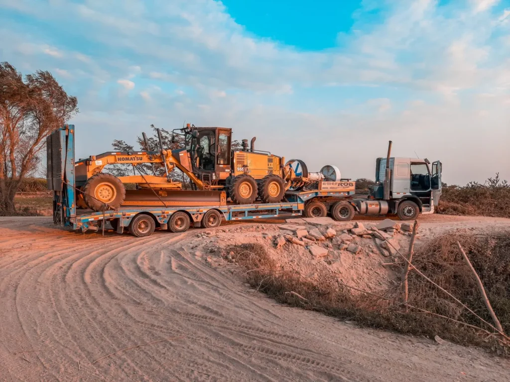 Truck transporting construction machinery on a dirt road