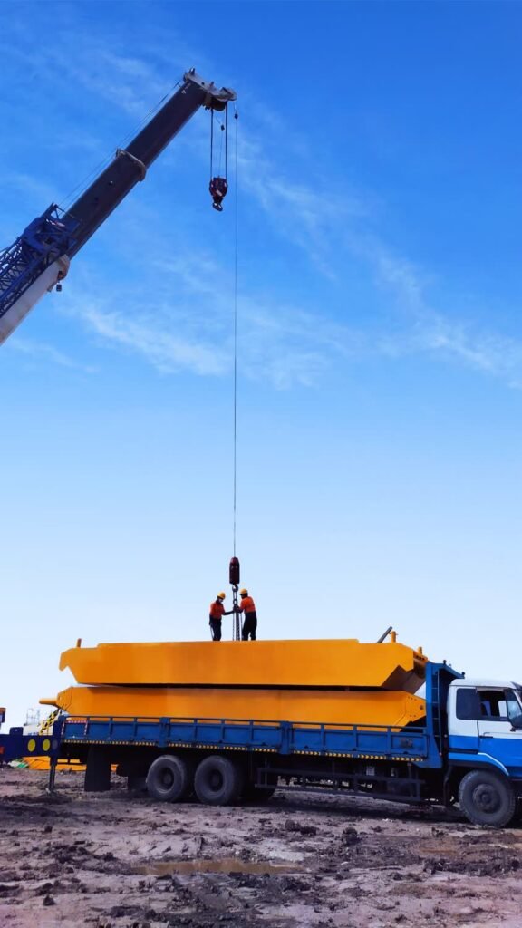 Crane lifting a large fabricated component onto a truck