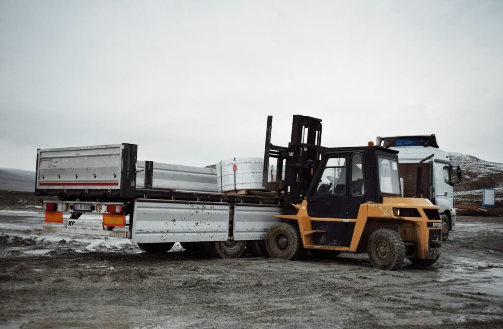 Forklift loading industrial materials onto a flatbed truck