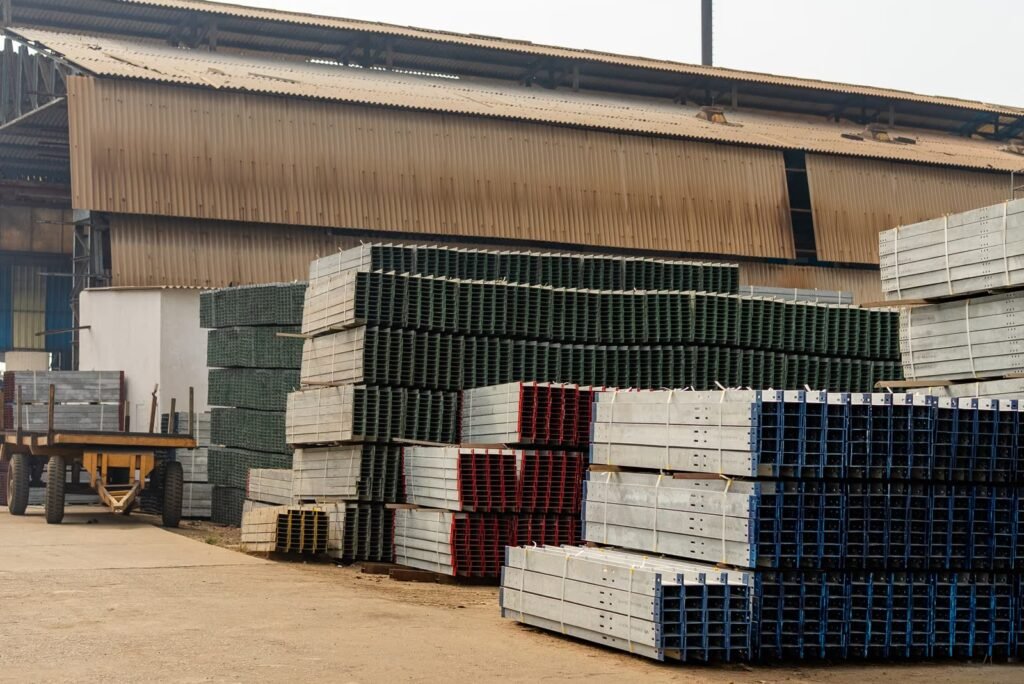 Stacks of metal beams outside an industrial warehouse