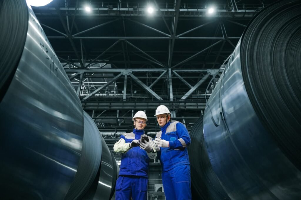 Industrial workers inspecting large steel coils in a plant