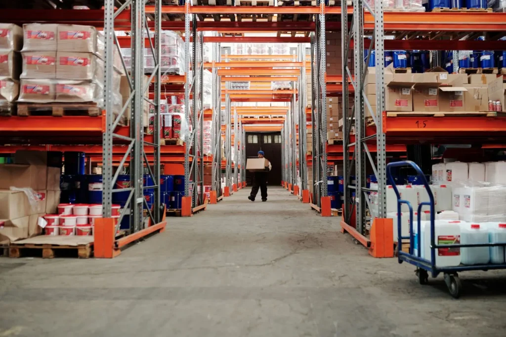 Worker carrying a cardboard carton along a warehouse aisle