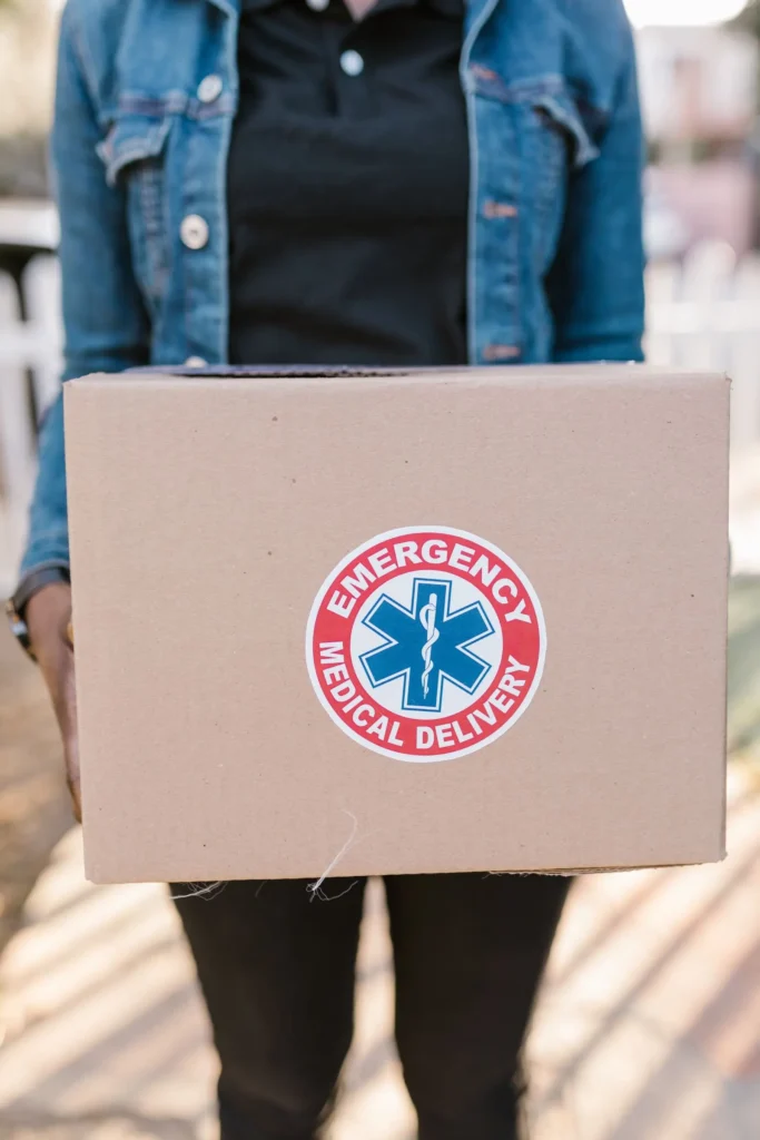 Person holding a cardboard box marked for emergency medical delivery