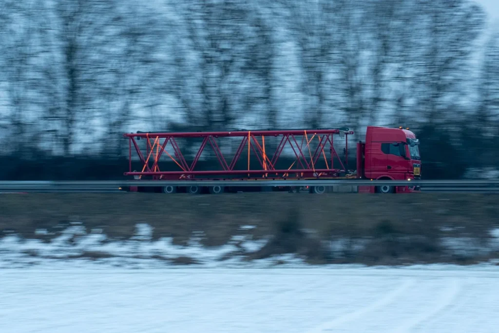 Truck carrying a large steel beam on a winter road