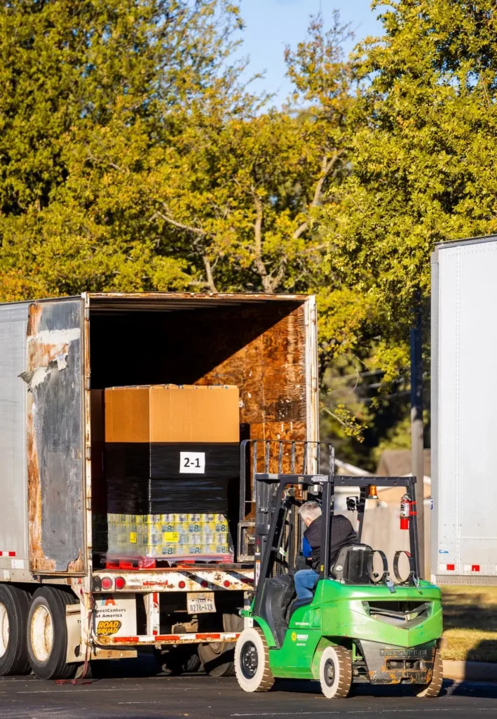 Forklift loading a pallet of boxed goods into a freight trailer
