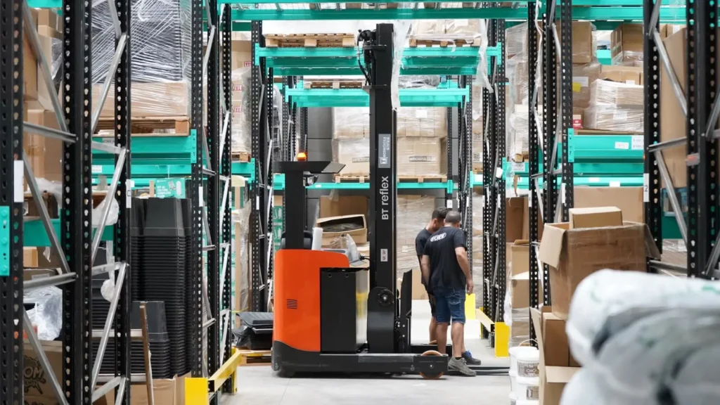 Forklift and workers among pallets in a warehouse