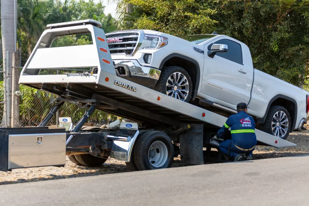 White pickup truck being loaded onto a rollback tow truck